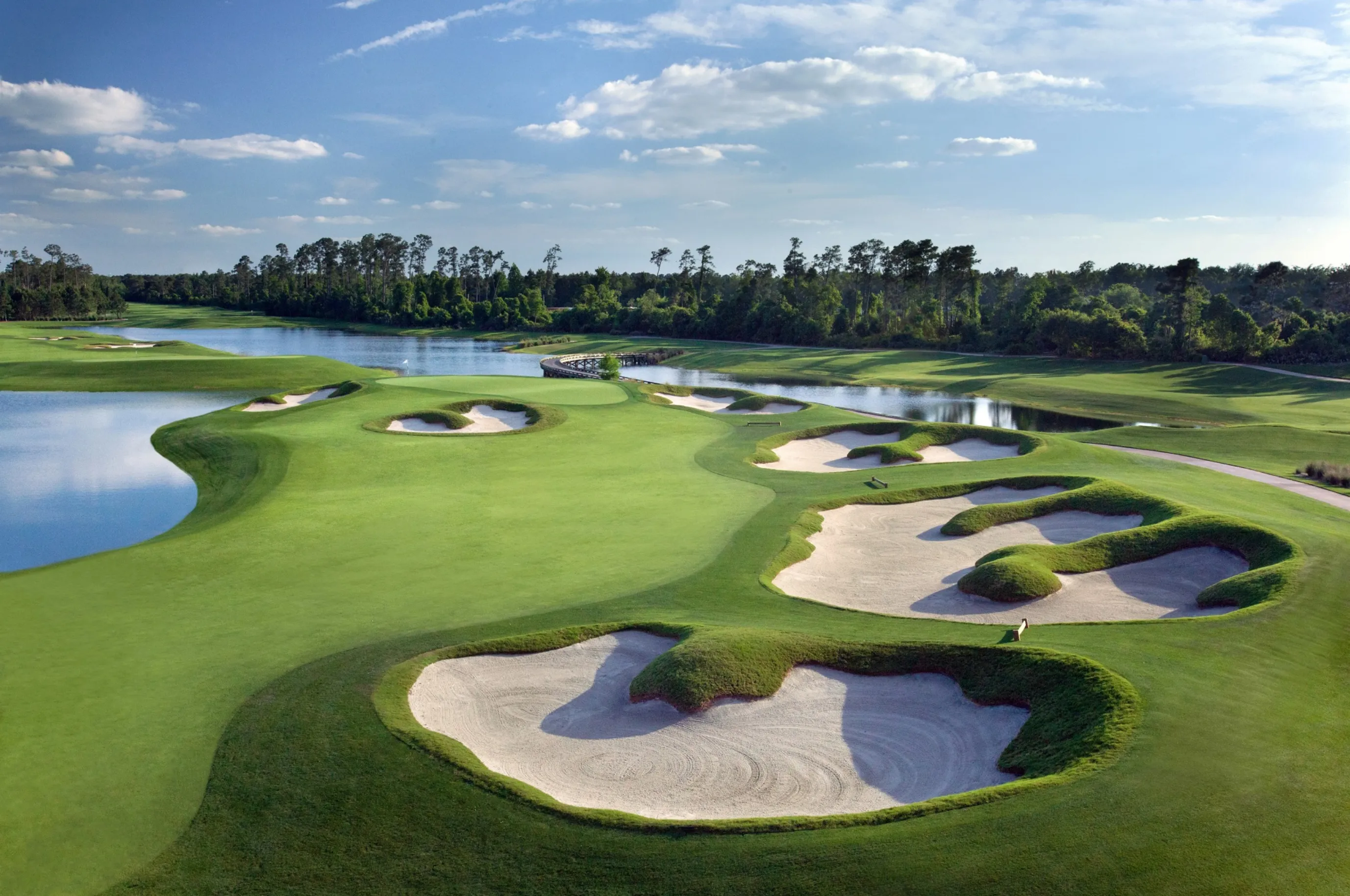 A golf course with bunkers and a lake in the background.