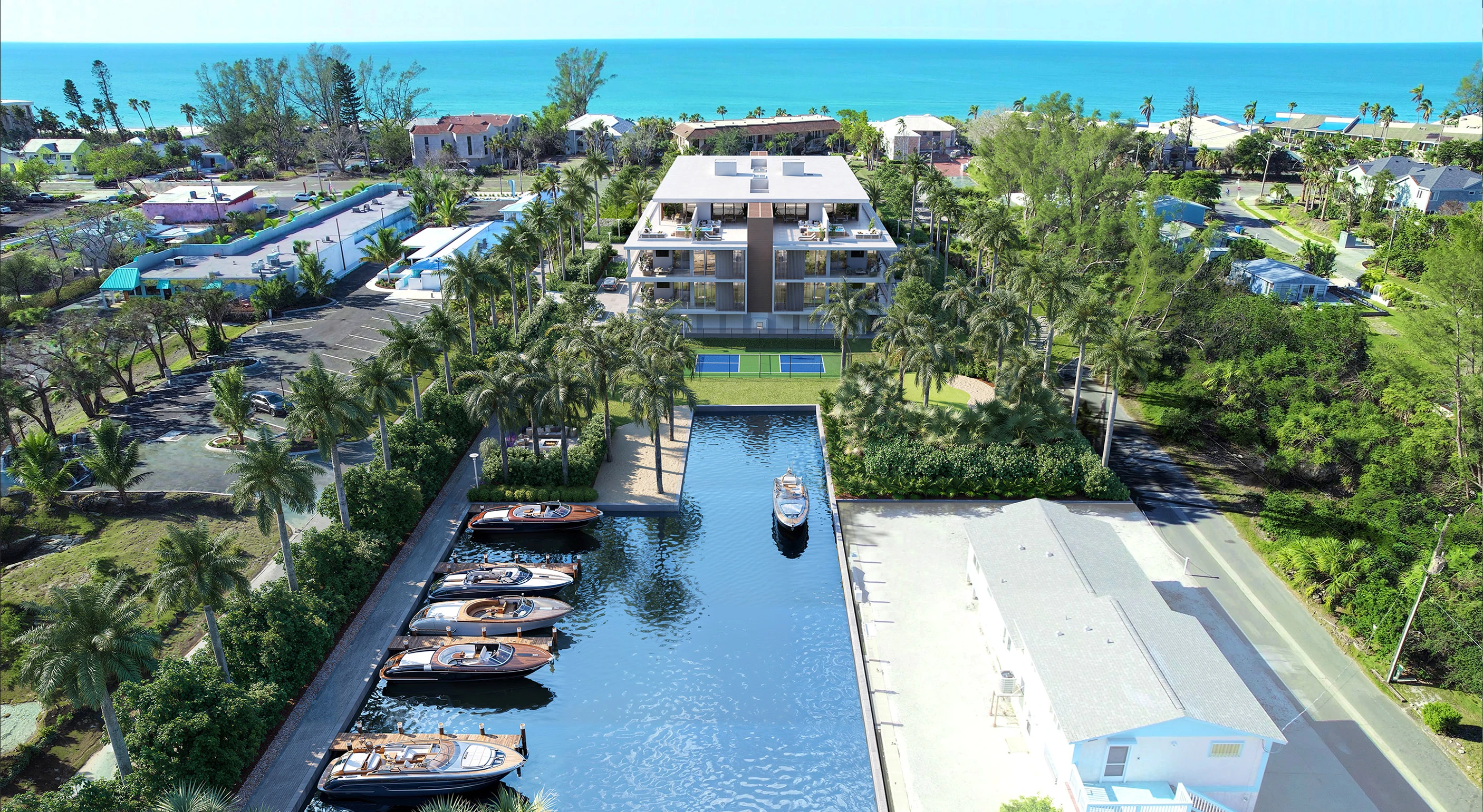 Aerial view of a modern beachfront resort with a central luxury building, surrounded by palm trees, a tennis court, and a private marina with yachts, set against a backdrop of ocean and coastal homes.
